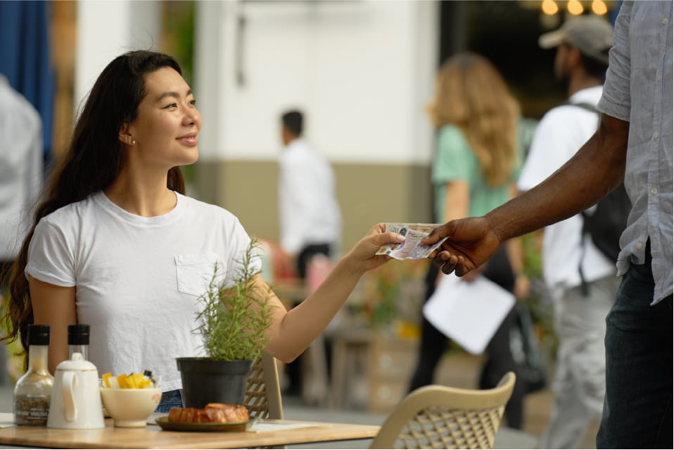 woman in cafe paying with cash
